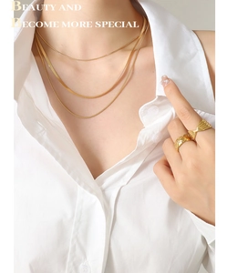 Gros plan sur le collier à trois couches dorées et les bagues minimalistes sur un mannequin