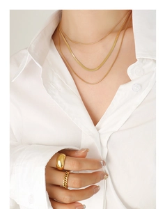 Gros plan d'un collier doré à trois rangs et de bagues empilables portés par un mannequin
