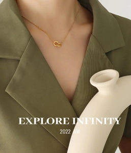 Detailed view of interlocking double ring pendant necklace on model with green blazer