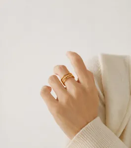 Detail of 18K gold plated multi-layer stackable geometric ring worn on index finger