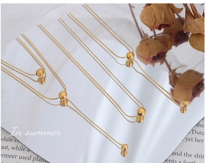 Detailed close-up of a minimalist gold layered ball necklace on elegant fabric