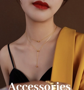 Detail of layered gold beaded necklace and Y-shaped tassel chain on female model