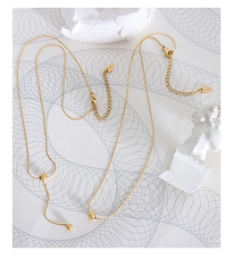 Detail of 18K gold minimalist layered bead necklaces featuring a K18 hallmark engraving