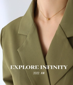 Close-up of a layered gold ball pendant necklace worn with a green blazer outfit