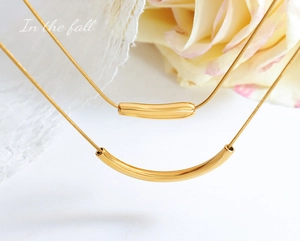 Macro view of gold plated layered snake chains with curved tubes and autumn aesthetic