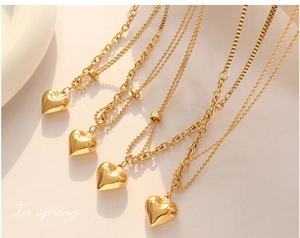 Macro detail of gold-plated 3D heart pendant necklace with layered bead and link chains