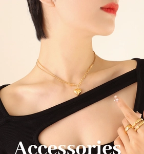 Close-up of gold heart pendant necklace with mixed link chain and matching rings