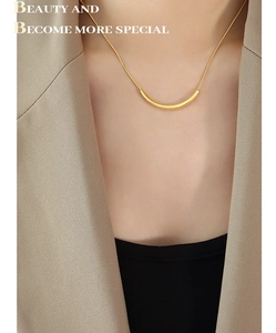 Detail view of a gold-toned smile curved bar pendant on a dainty titanium chain