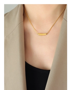 Close-up of minimalist gold plated smiley pendant necklace on a sleek snake chain
