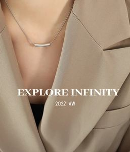 Close-up of a silver minimalist curved bar pendant necklace on a khaki suit jacket