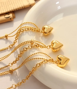 Detailed macro shot of a gold 3D heart pendant necklace on a ceramic tray with newspaper
