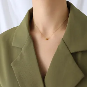 Minimalist double layer titanium necklace with gold beads on elegant dark green blazer