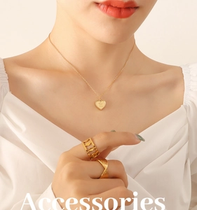 Détail du pendentif cœur doré avec gravure Love You More et ensemble de bagues