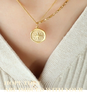 Detail einer mehrlagigen goldenen Titan-Halskette mit Stern-Anhänger an einem Model