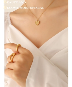 Détail du collier cœur doré mat gravé love you more avec des bagues torsadées élégantes