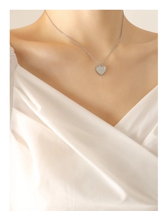Détail du pendentif cœur argenté avec bord perlé et chaîne à maillons fins