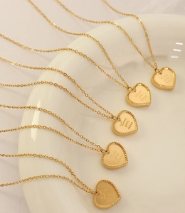 Gros plan de pendentifs cœur dorés avec gravure Love You More et bordure perlée