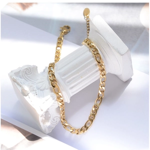 Detail of a vintage golden Figaro chain anklet wrapped on a white classic plaster column