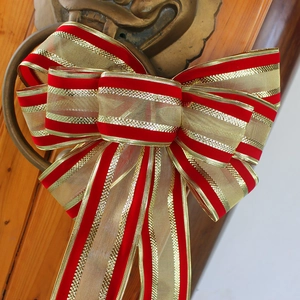 Large Christmas bow with red velvet and gold stripes on a vintage door knocker