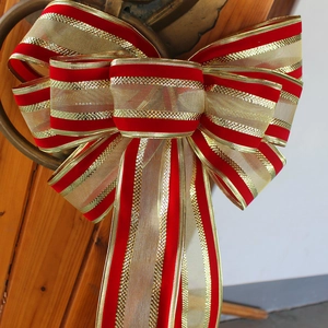 Large Christmas velvet bow with gold stripes hanging on a vintage metal door knocker