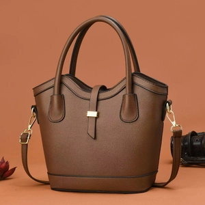Detail of caramel brown bucket bag with lychee texture leather and gold metal buckle