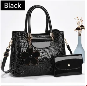 Detail of black crocodile pattern tote bag set with floral charm and glossy finish