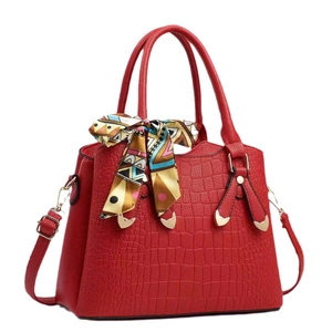 Sac à main rouge en cuir croco avec détails dorés et un foulard en soie décoratif