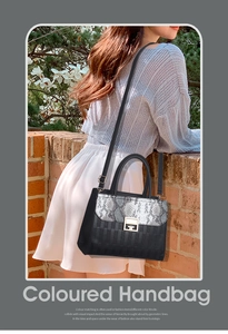 Detail of elegant black and grey snakeskin handbag with golden G-lock and shoulder strap