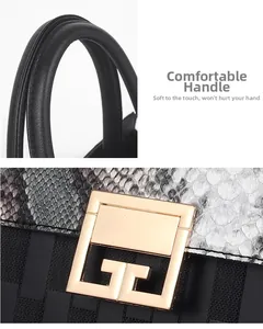 Detail of snake skin texture and gold G-shaped metal buckle on black leather handbag