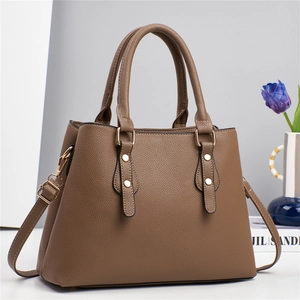 Detail of dark brown pebble leather handbag featuring gold rivets and detachable strap