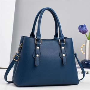 Detailed view of navy blue pebble leather handbag with gold studs and shoulder strap