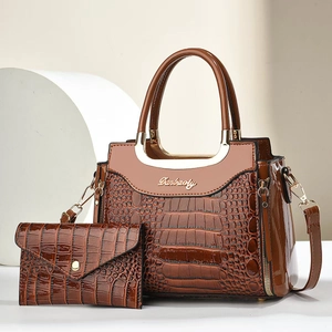 Detail of crocodile embossed tote and matching envelope wallet with metallic ring handle