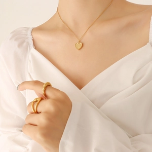 Pendentif cœur doré élégant et ensemble de bagues assorties portés par un modèle