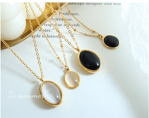 Détails de pendentifs vintage en œil de chat sur chaînes perlées dorées, noir et blanc