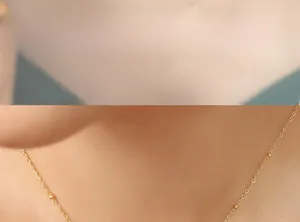 Détail d'un collier doré vintage avec perles et pendentif opale sur le cou du modèle