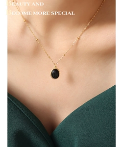 Gros plan d'une chaîne dorée avec pendentif ovale noir en œil de chat sur le cou