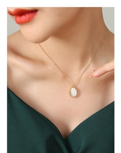 Gros plan d'un collier en titane doré avec pendentif oeil de chat sur un mannequin