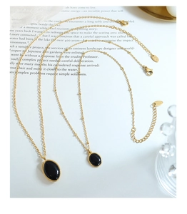 Détail de colliers en titane doré vintage avec pendentifs opale noire sur fond magazine