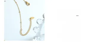 Gros plan d'un collier doré avec plaque gravée K18, fermoir mousqueton et chaînette