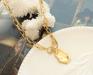 Detailed shot of double-layer gold necklace with irregular pendant and OT clasp