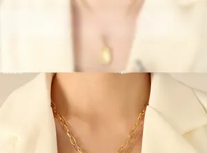 Close-up of layered gold geometric necklace with mixed chain links on a chic white suit