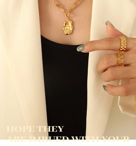 Detailed view of layered gold irregular pendant necklace and matching textured rings on model