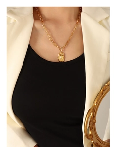 Detail of irregular lava texture gold pendant with layered double chain on model