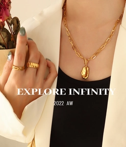 Close-up of double-layer gold necklace with irregular lava pendant and textured rings