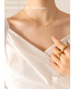 Detail of gold heart pendant necklace with textured spiral rings worn by a model