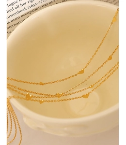 Detailed macro shot of a gold heart pendant necklace on a cream ceramic bowl edge
