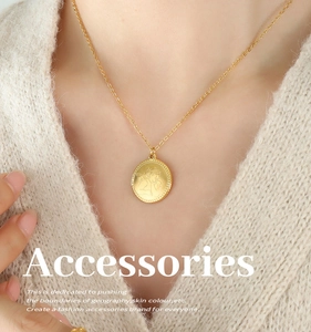 Modella indossa una collana con ciondolo angelo Cupido oro su maglione beige