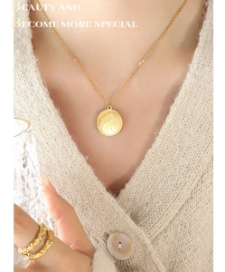 Dettaglio della collana con medaglia angelo dorata indossata da modella con anello