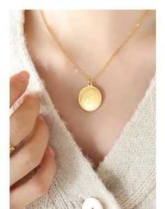 Dettaglio della collana con medaglia angelo dorata e anello abbinato su maglia