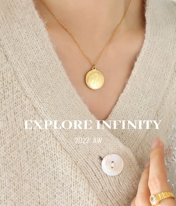 Dettaglio della collana con medaglia angelo e anello a coste su cardigan in maglia
